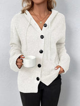 Women's white cozy knit hooded button-down cardigan with black buttons, soft lightweight sweater paired with black pants for casual fall style.