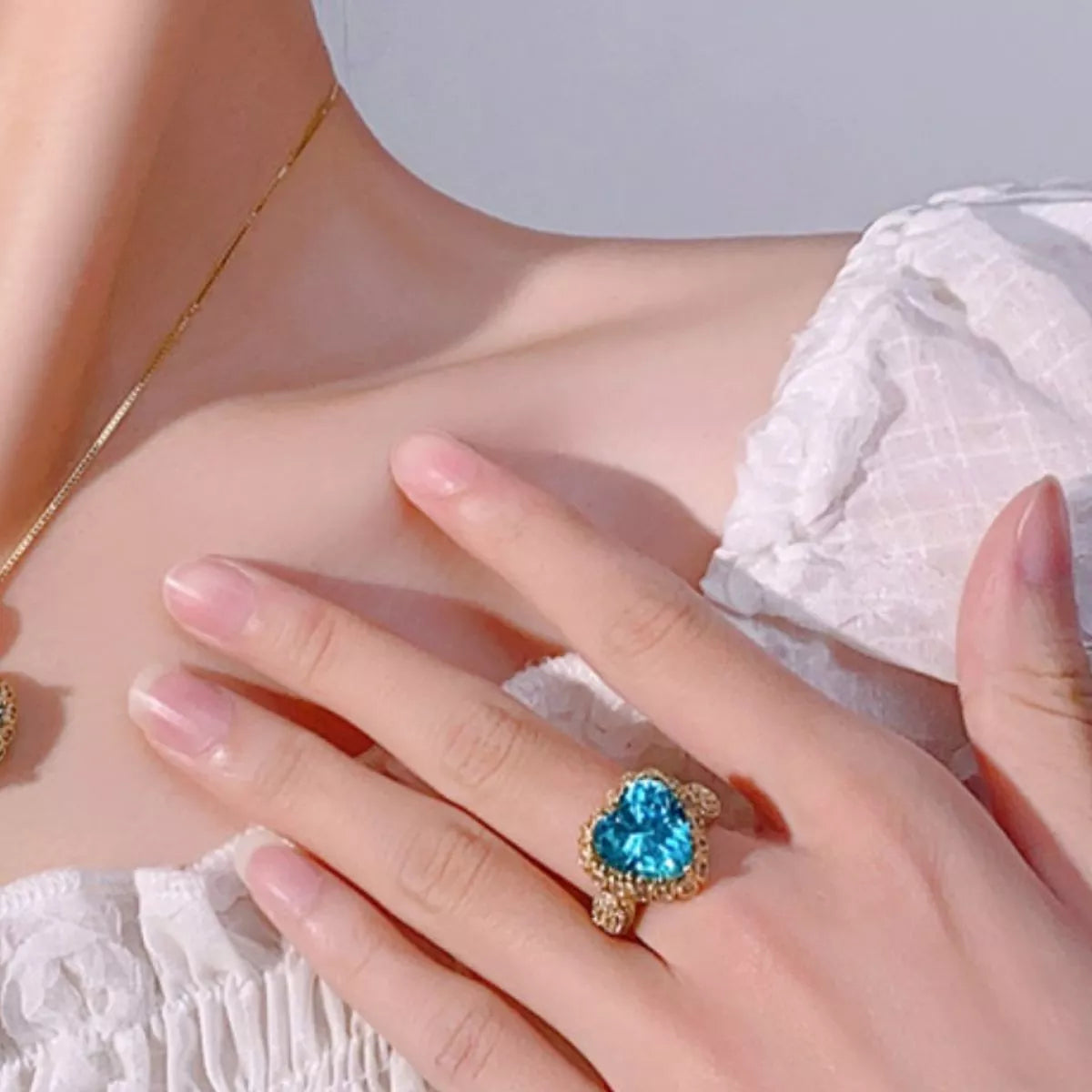 18K gold-plated heart-shaped ring featuring a brilliant aquamarine-colored center stone surrounded by sparkling zircon accents.