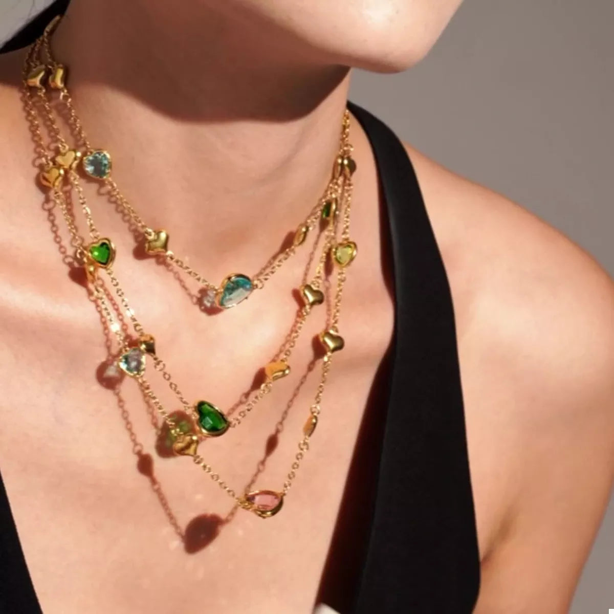 18K gold-plated heart necklace featuring a heart-shaped glass stone available in dark green, light blue, and blush pink with delicate gold heart accents.