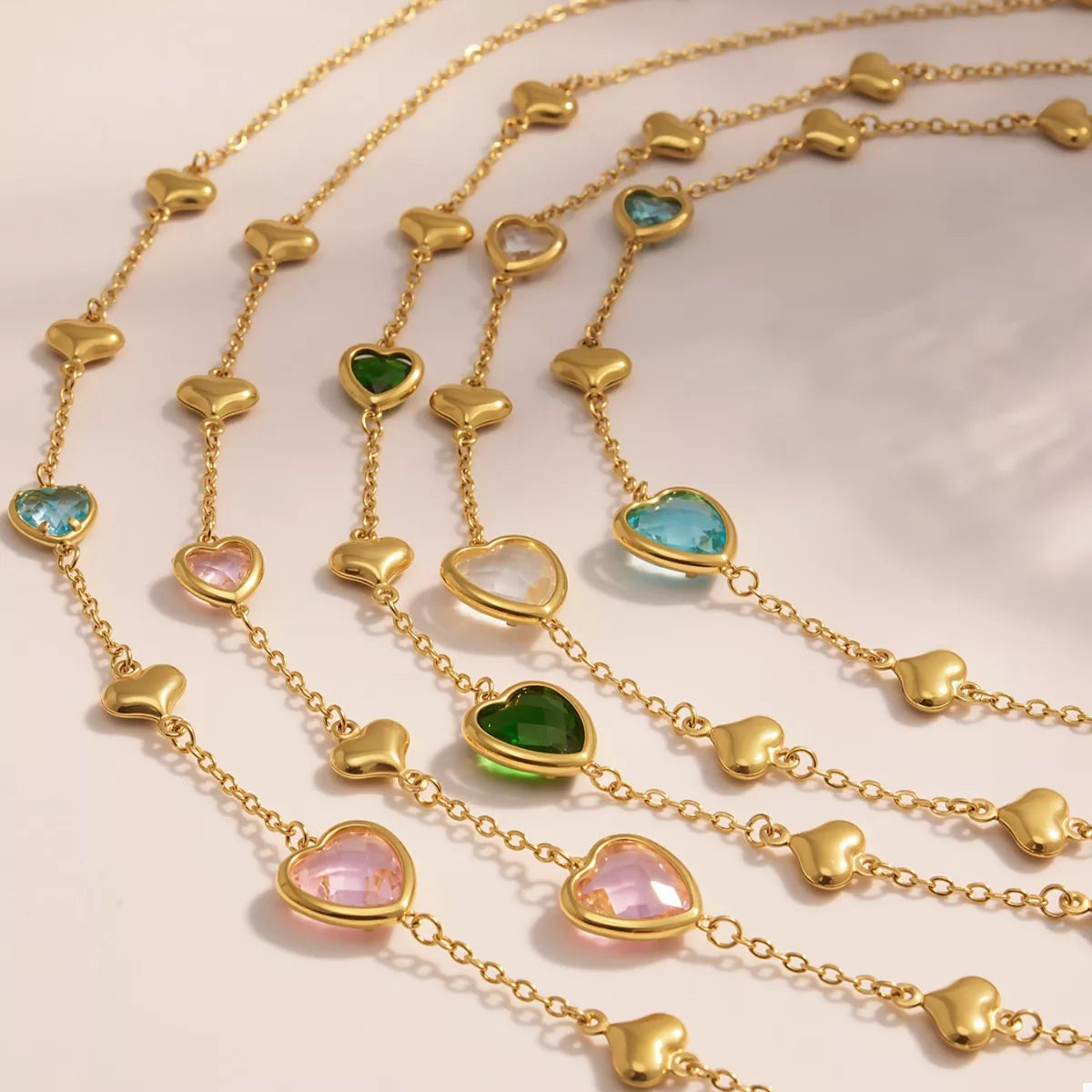 18K gold-plated heart necklace featuring a heart-shaped glass stone available in dark green, light blue, and blush pink with delicate gold heart accents.
