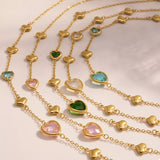 18K gold-plated heart necklace featuring a heart-shaped glass stone available in dark green, light blue, and blush pink with delicate gold heart accents.