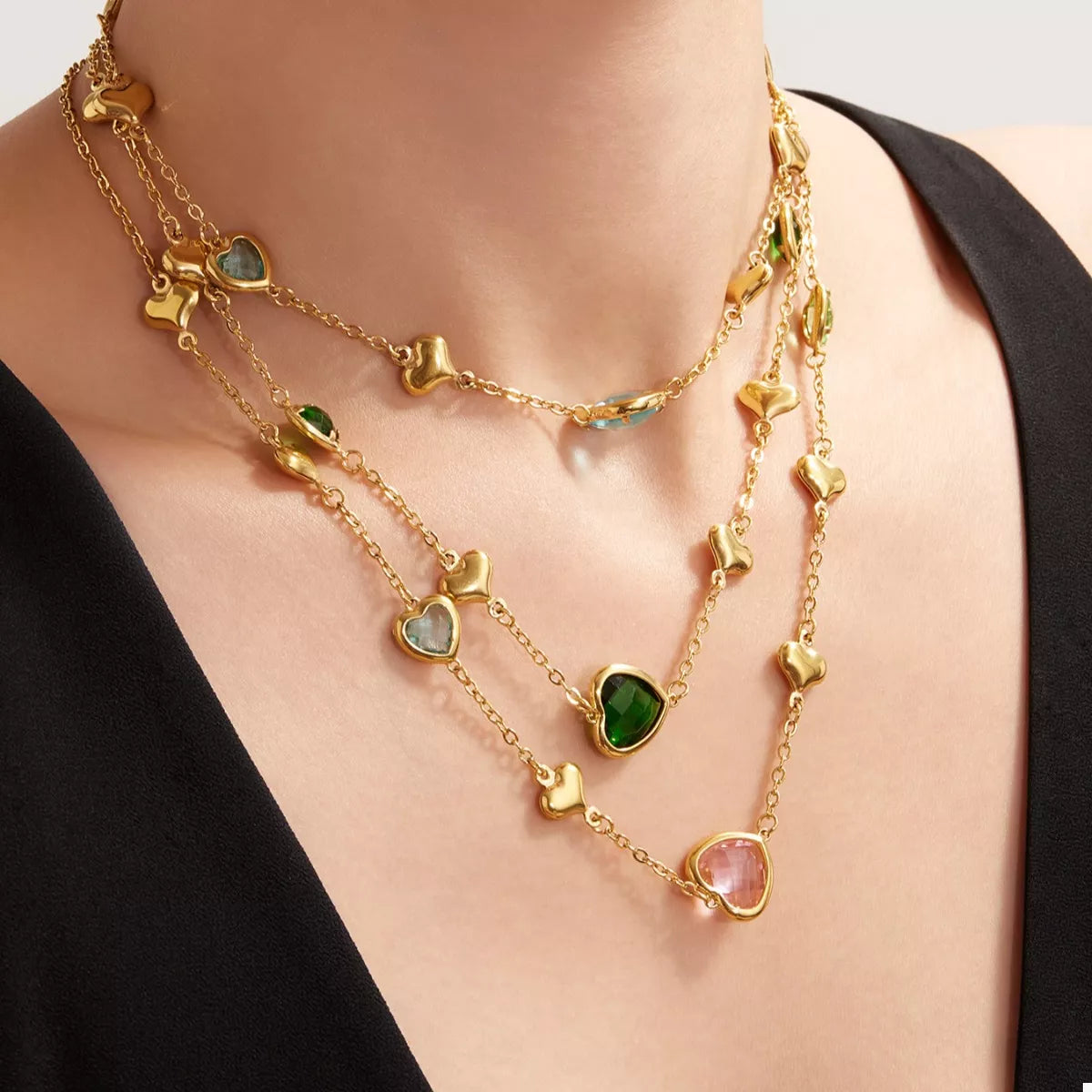 18K gold-plated heart necklace featuring a heart-shaped glass stone available in dark green, light blue, and blush pink with delicate gold heart accents.