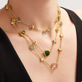 18K gold-plated heart necklace featuring a heart-shaped glass stone available in dark green, light blue, and blush pink with delicate gold heart accents.