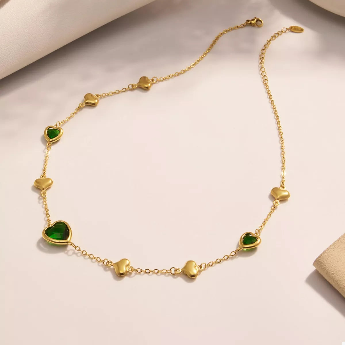 18K gold-plated heart necklace featuring a heart-shaped glass stone available in dark green, light blue, and blush pink with delicate gold heart accents.