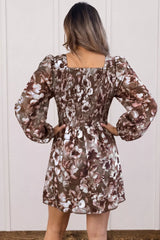 Woman wearing an abstract floral print square neck long sleeve mini shift dress in warm brown tones with a relaxed fit, perfect for fall styling.