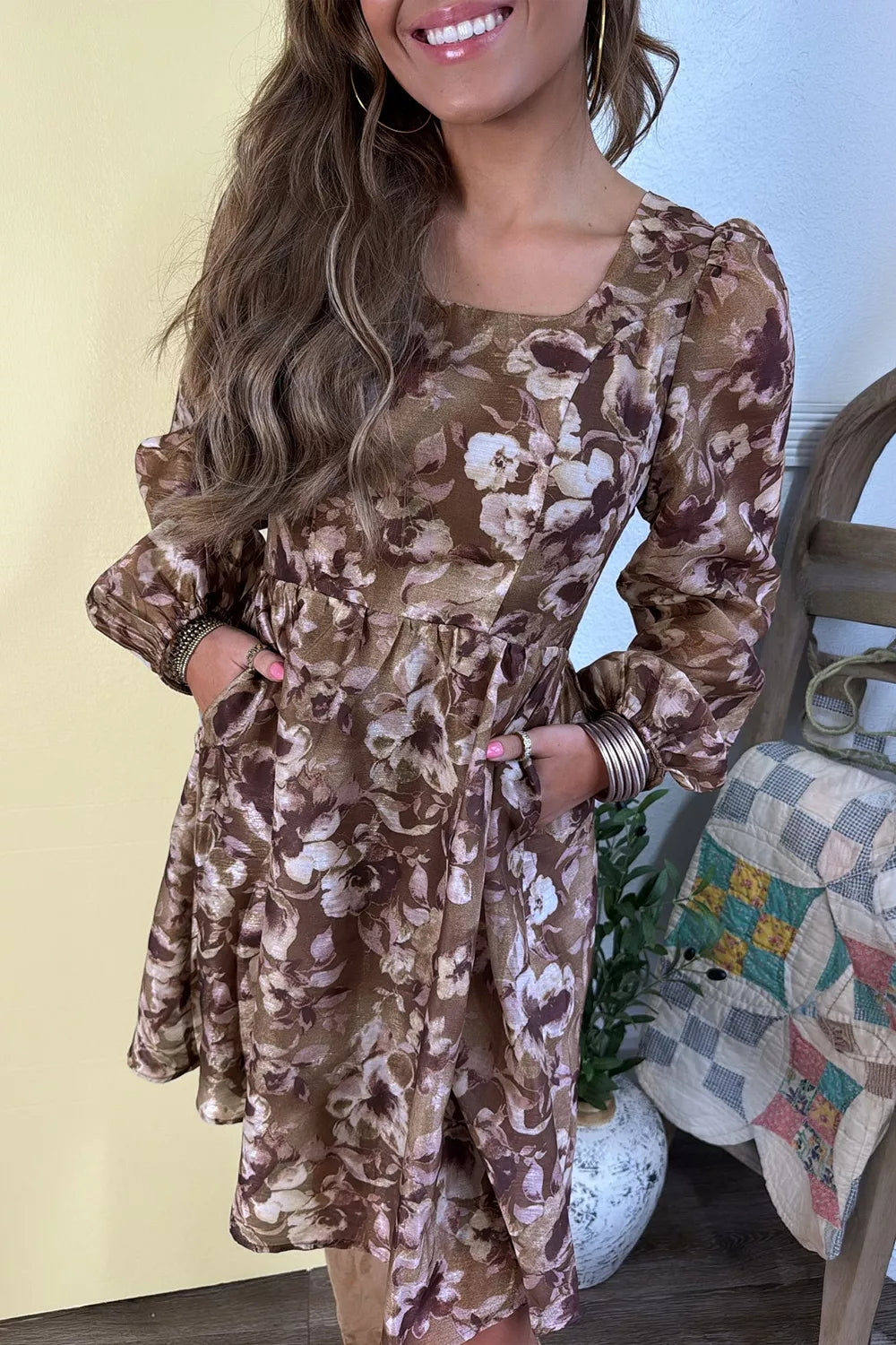 Woman wearing an abstract floral print square neck long sleeve mini shift dress in warm brown tones with a relaxed fit, perfect for fall styling.