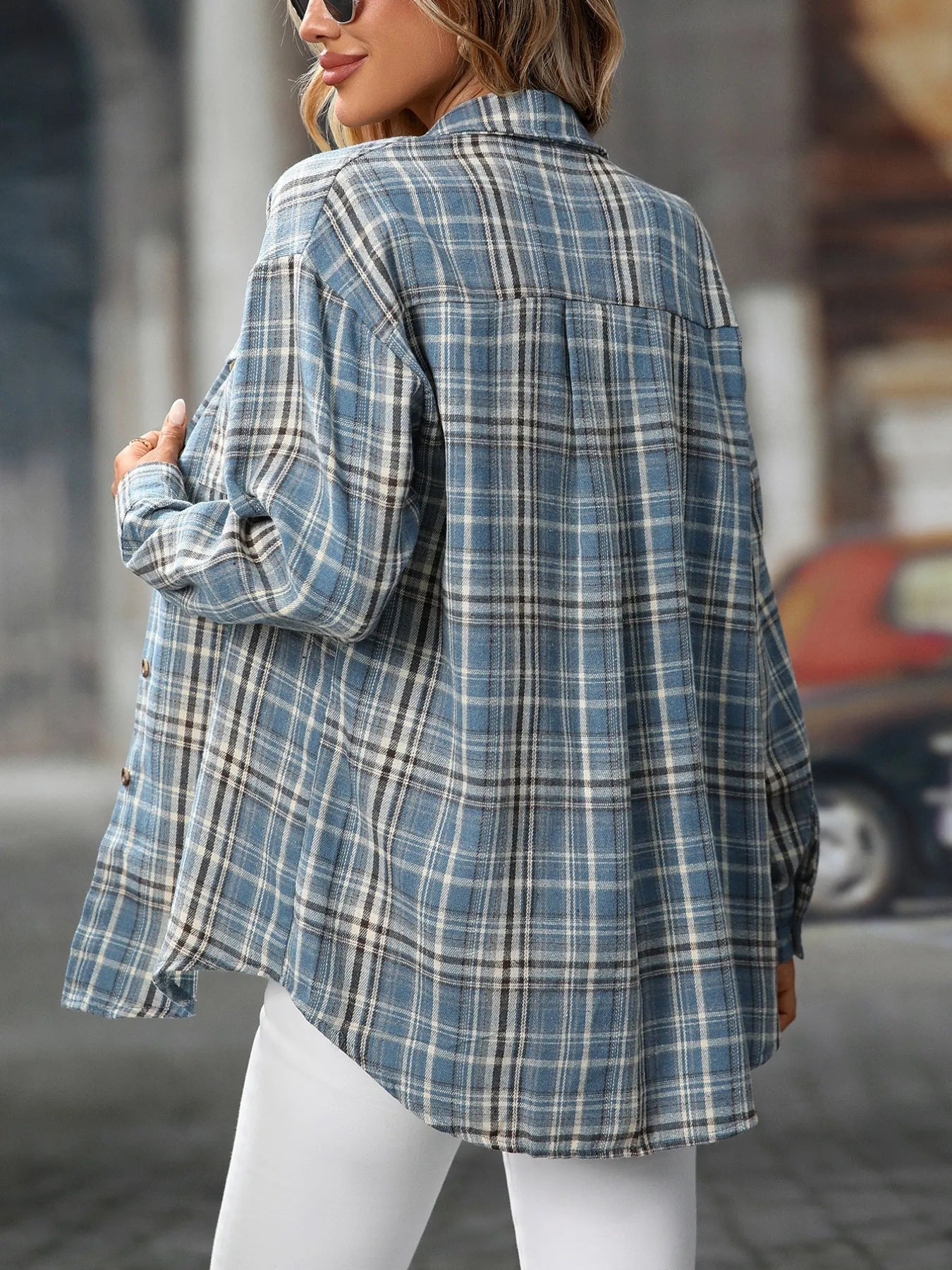 Woman wearing an air force blue plaid oversized button-up shirt layered over a white top with white jeans.