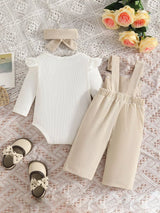 Baby girl three-piece outfit featuring a cream ribbed long-sleeve bodysuit with ruffled shoulders, apricot color bow-embroidered overalls and matching apricot bow headband.