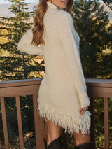 Woman wearing an apricot fringe turtleneck long sleeve sweater dress with brown knee-high boots, a cozy fall outfit from Chic Mystik Boutique.