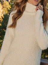 Woman wearing an apricot fringe turtleneck long sleeve sweater dress with brown knee-high boots, a cozy fall outfit from Chic Mystik Boutique.