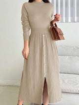 Woman wearing an apricot mock neck long sleeve knit midi dress with pleated skirt, front buttons and slit.