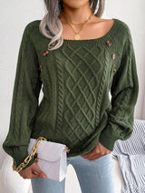 Woman wearing an army green cable-knit sweater with decorative buttons, paired with light-wash jeans, layered gold necklaces, and a white handbag. Perfect for cozy fall and winter outfits.
