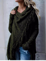 Woman wearing an army green fringe long sleeve wrap cardigan with an asymmetrical draped front over a white top and jeans.