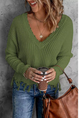 Woman wearing an army green ribbed V-neck sweater with distressed raw hem and blue jeans.