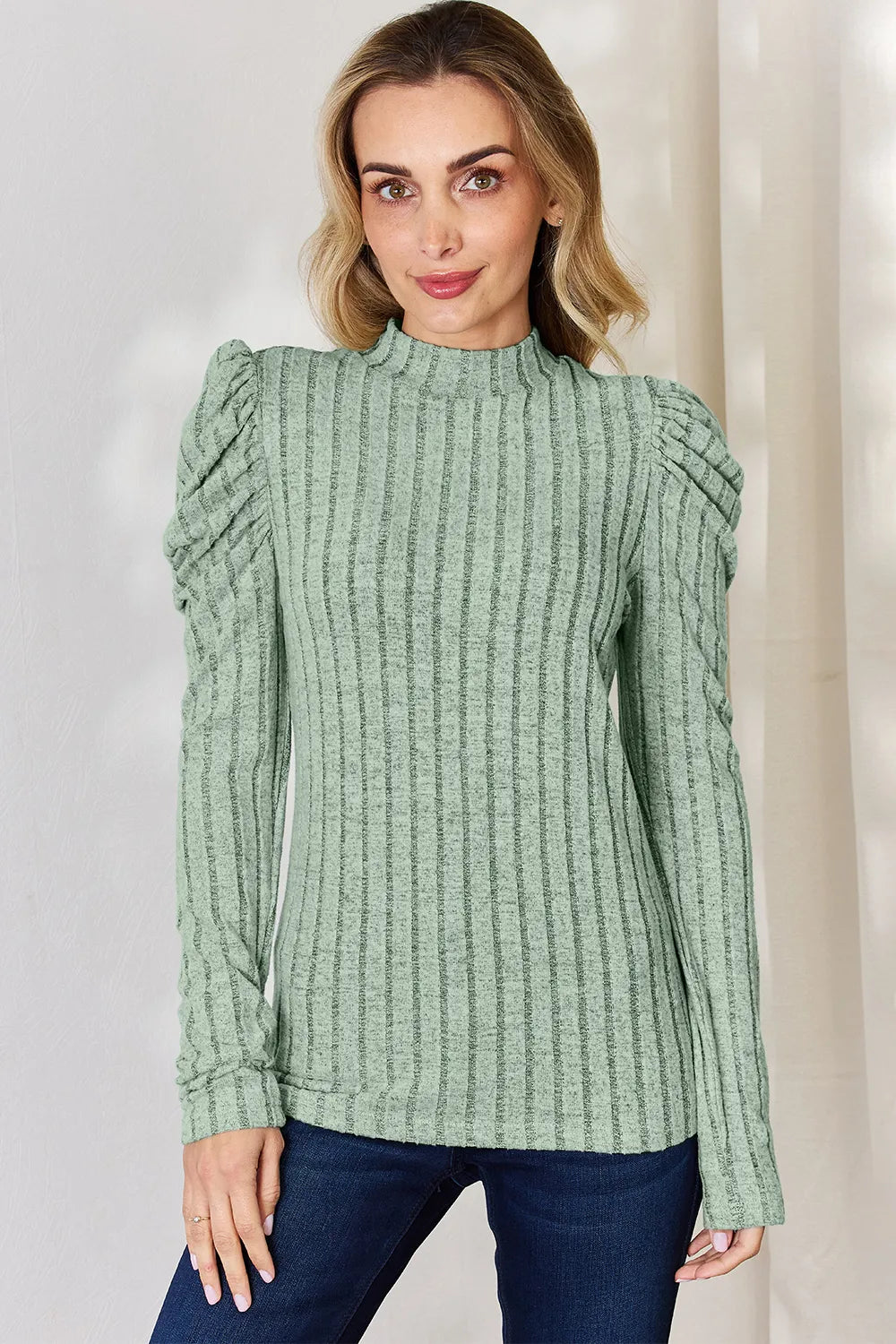 Woman wearing a light green Basic Bae ribbed mock neck long sleeve top with ruched puff shoulders, paired with dark blue jeans.