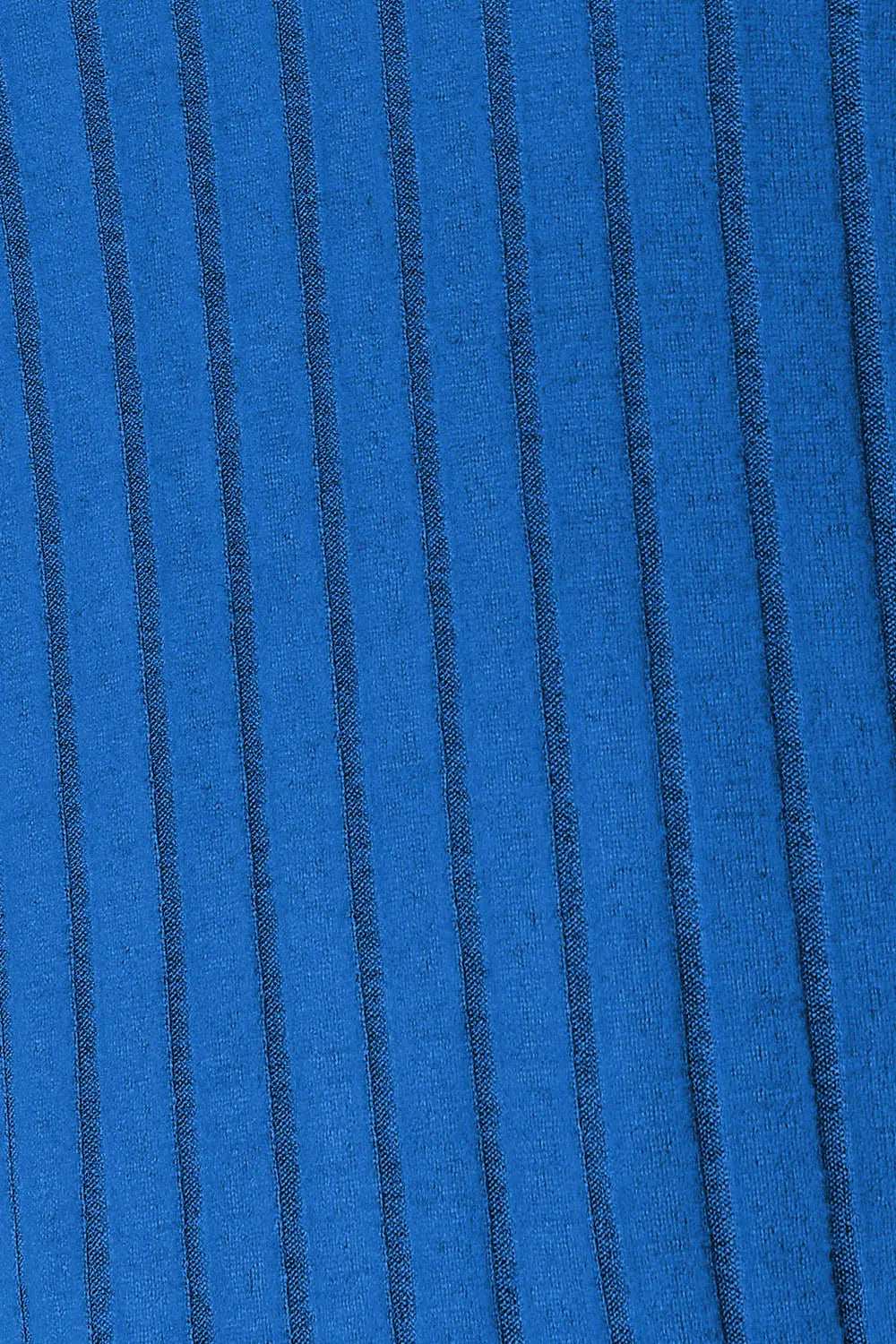 Woman wearing a blue ribbed long sleeve knit top with a round neckline and side slit detail.