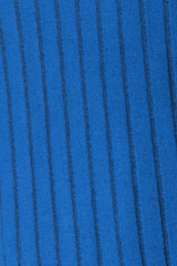 Woman wearing a blue ribbed long sleeve knit top with a round neckline and side slit detail.
