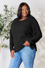 Woman wearing a black ribbed long sleeve knit top with a round neckline and side slit detail.