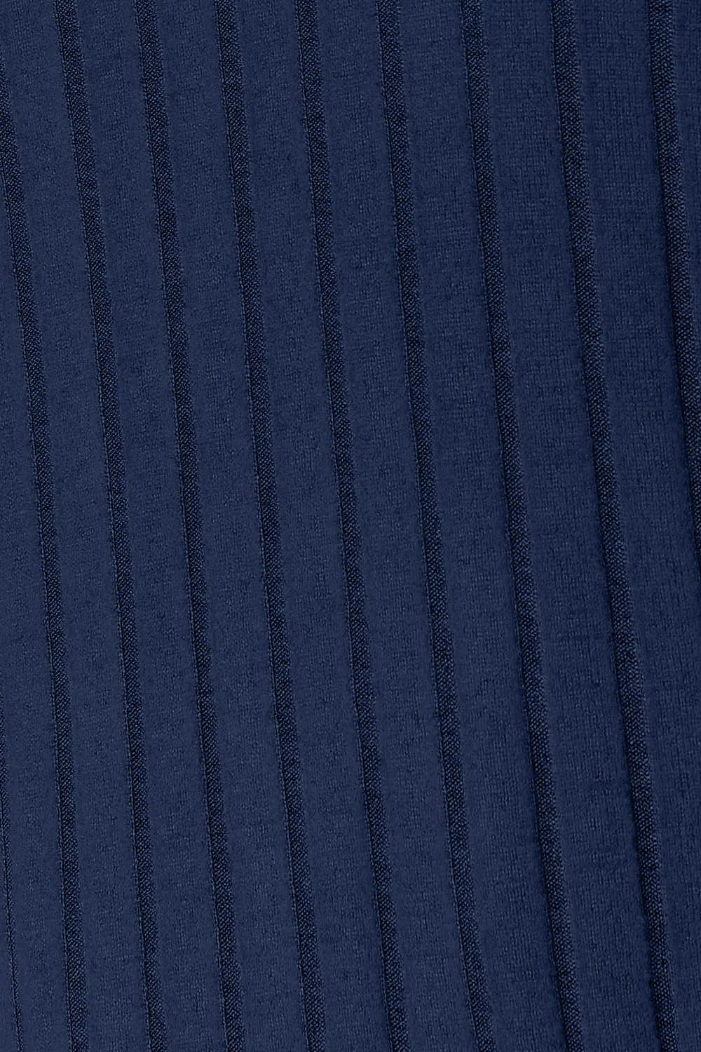 Woman wearing a dark blue ribbed long sleeve knit top with a round neckline and side slit detail.