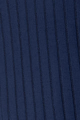 Woman wearing a dark blue ribbed long sleeve knit top with a round neckline and side slit detail.