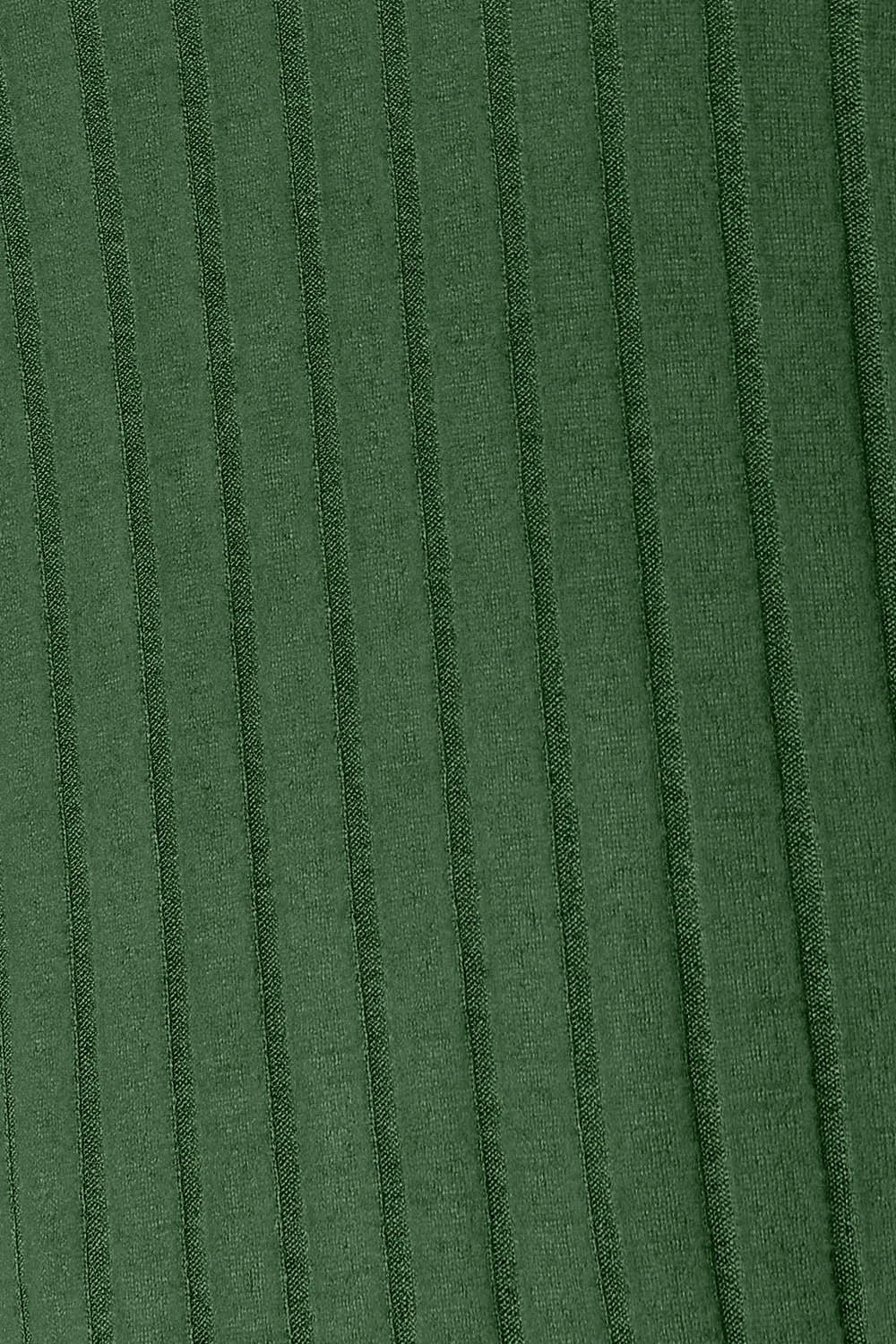 Woman wearing a dark green ribbed long sleeve knit top with a round neckline and side slit detail.
