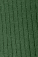 Woman wearing a dark green ribbed long sleeve knit top with a round neckline and side slit detail.