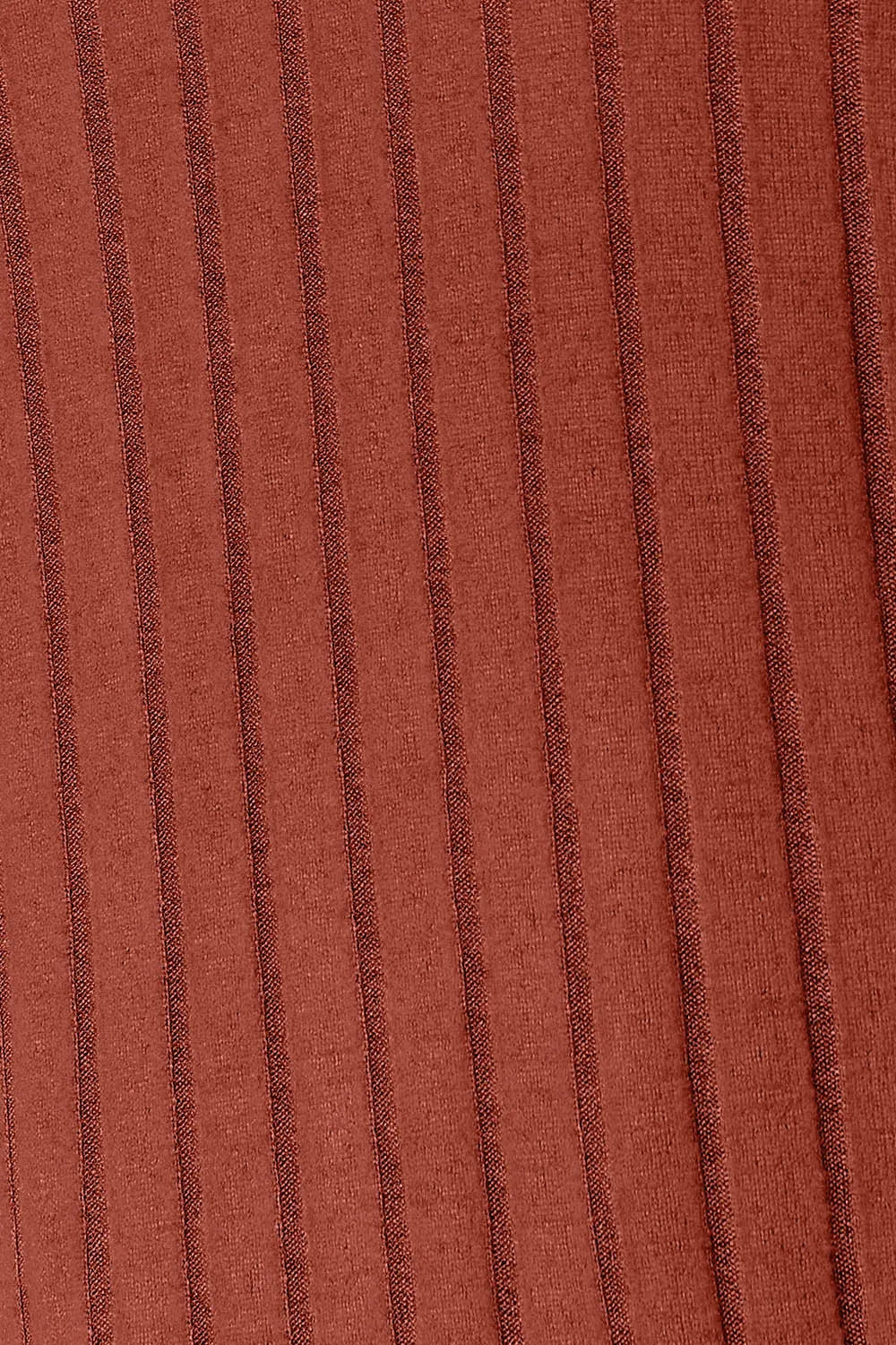 Woman wearing a rust ribbed long sleeve knit top with a round neckline and side slit detail.