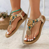 Beige sandals with colorful embellishments worn by a person on a light background