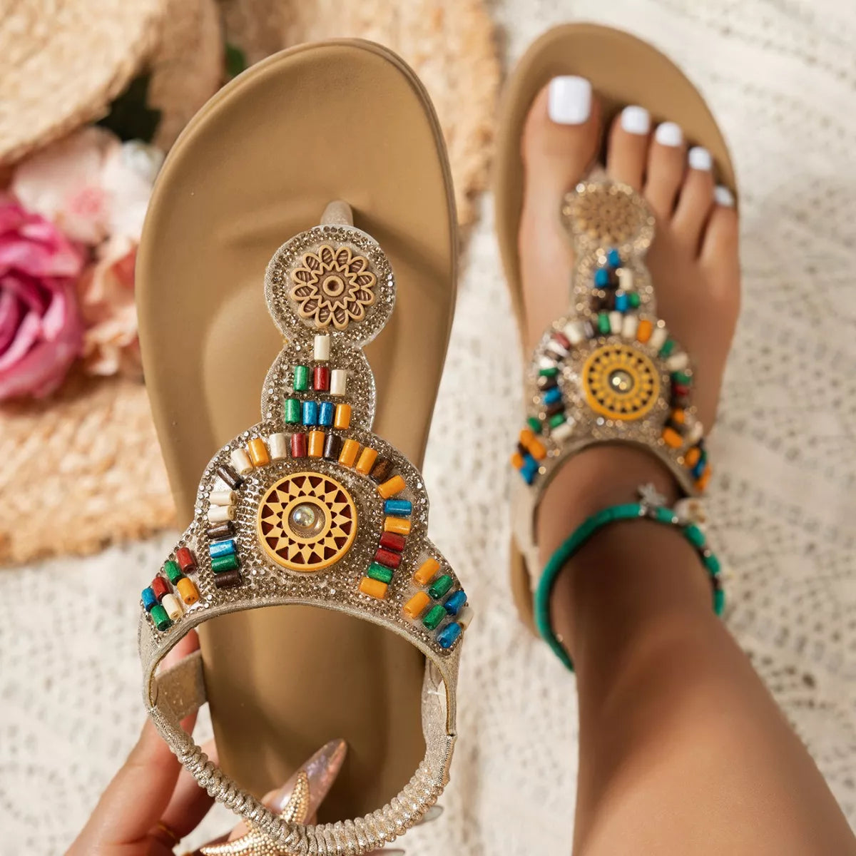 Decorative sandals with colorful beads worn on a textured surface.