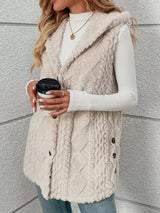 Woman wearing a beige hooded sherpa vest coat over a white long-sleeve top with blue jeans for a cozy fall and winter outfit.
