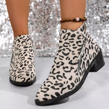 Woman wearing beige leopard-print ankle boots with block heels and side zipper details.