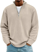 Man wearing a beige ribbed corduroy quarter zip pullover sweatshirt layered over a white shirt.