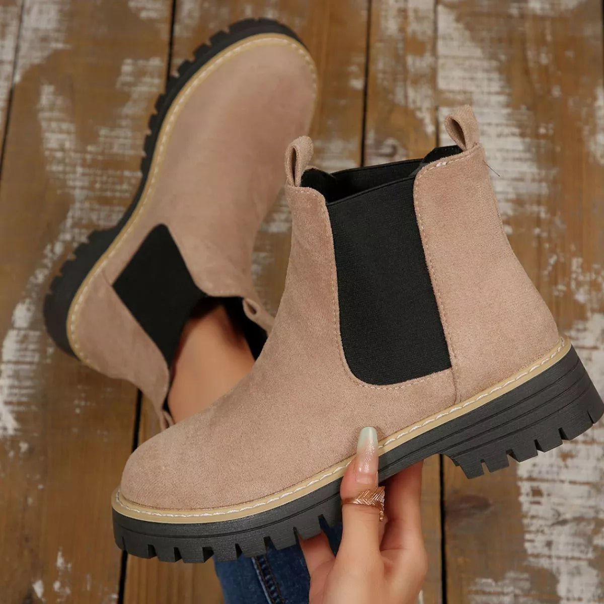 Beige suede round toe Chelsea ankle boots with black elastic side panels, mid-block heels and lug soles.