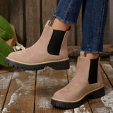 Beige suede round toe Chelsea ankle boots with black elastic side panels, mid-block heels and lug soles.