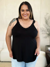 Woman wearing a black colored Basic Bae lace-detail V-neck cami with delicate lace trim and cutout accents, styled with dark-wash jeans for a chic casual look.