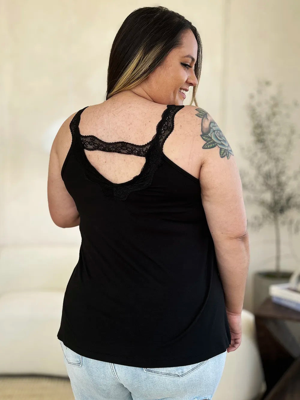 Woman wearing a black colored Basic Bae lace-detail V-neck cami with delicate lace trim and cutout accents, styled with dark-wash jeans for a chic casual look.