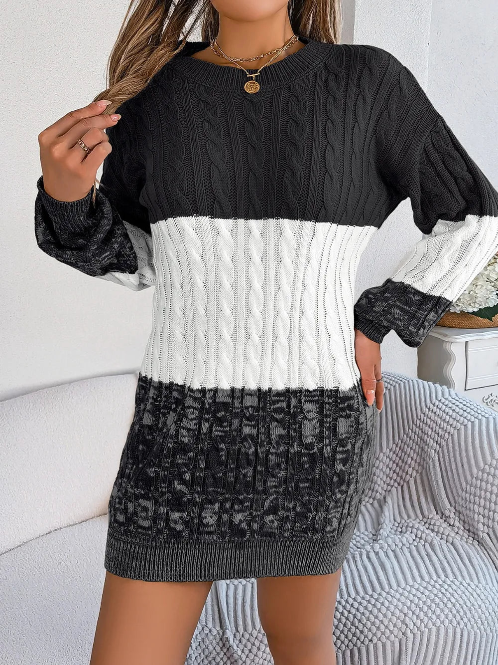 Women's black cable-knit round neck color block sweater dress with long sleeves and textured knit design.
