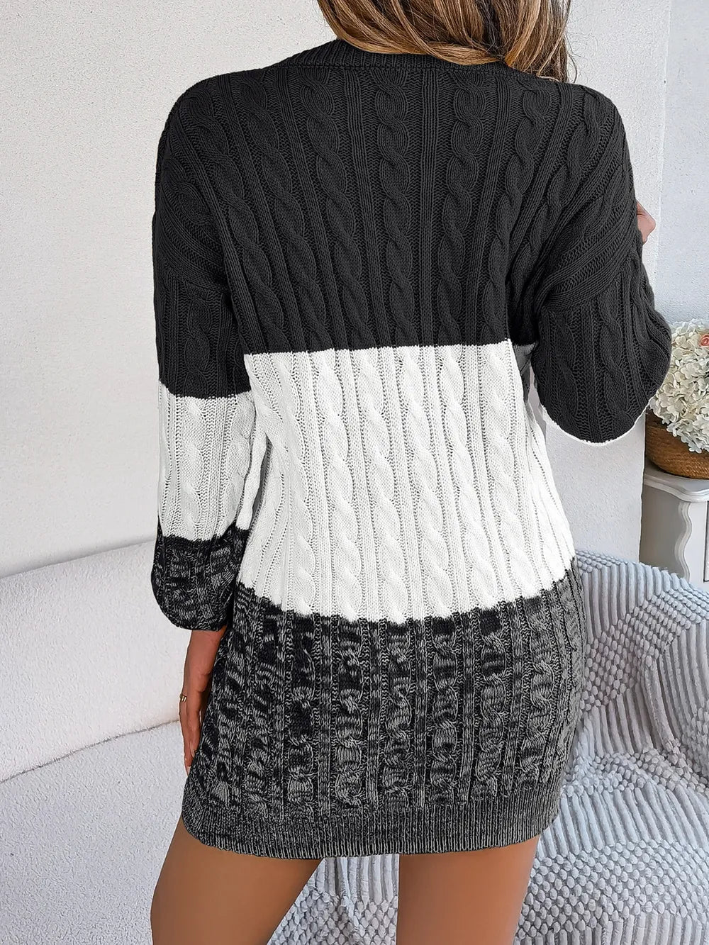 Women's black cable-knit round neck color block sweater dress with long sleeves and textured knit design.