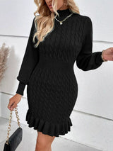 Woman wearing a black cable-knit sweater mini dress with mock neckline, long sleeves, fitted waist and feminine ruffled hem.