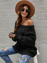 Woman wearing a black cable knit openwork off-shoulder sweater with distressed jeans and a wide-brim hat.