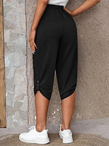 Model wearing black roll-tab capri pants with side pockets and white sneakers for a casual outdoor look.