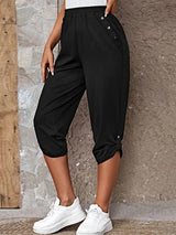 Model wearing black roll-tab capri pants with side pockets and white sneakers for a casual outdoor look.