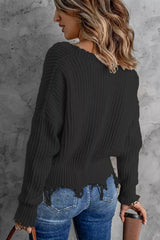 Woman wearing a black ribbed V-neck sweater with distressed raw hem and blue jeans.