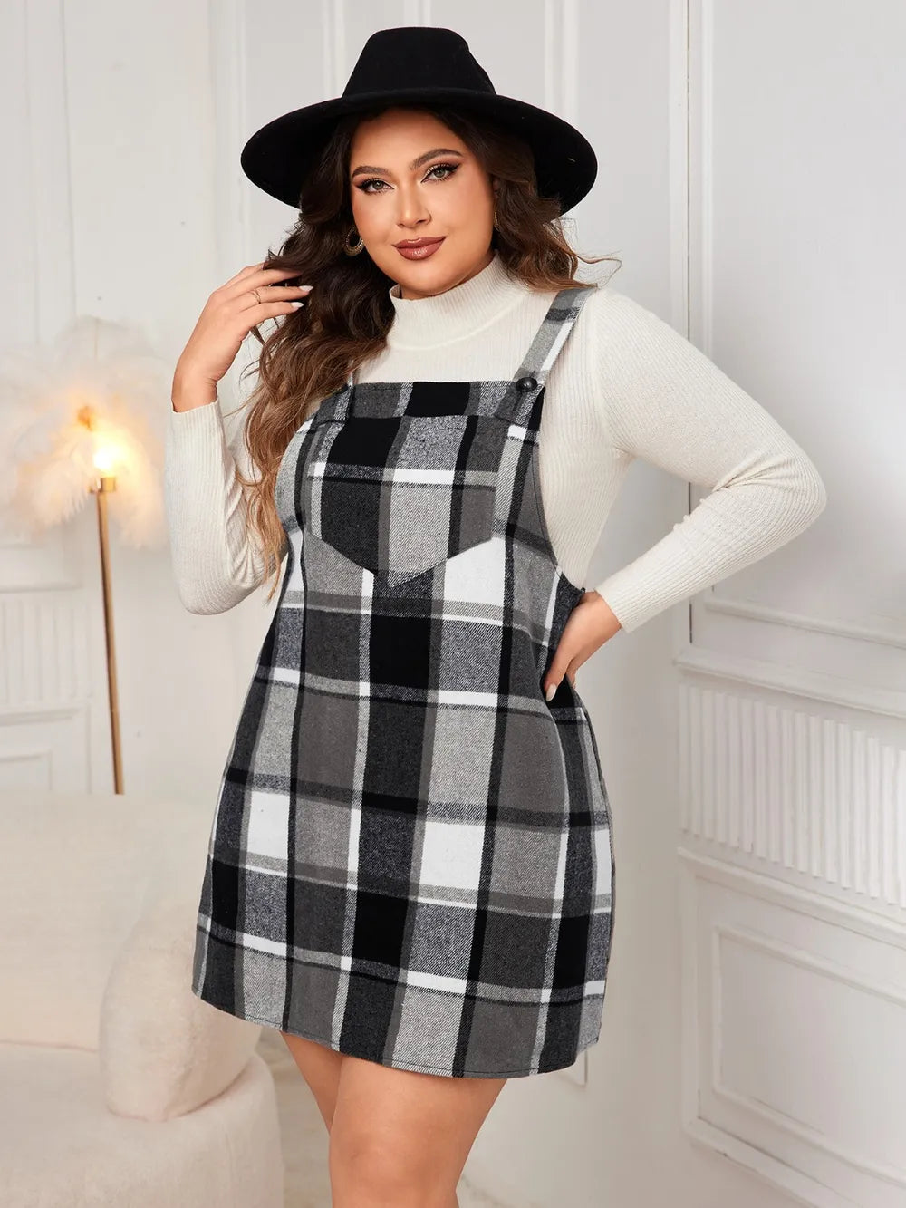 Woman wearing the Honey Plus Size Plaid Wide Strap Overall Dress layered over a cream mock neck sweater with a black felt hat, stylish plus size plaid fall dress from Chic Mystik Boutique.