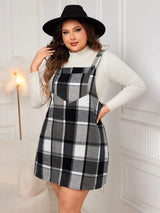 Woman wearing the Honey Plus Size Plaid Wide Strap Overall Dress layered over a cream mock neck sweater with a black felt hat, stylish plus size plaid fall dress from Chic Mystik Boutique.