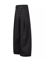 Men’s asymmetrical button wide-leg pants in coffee and black with pleated front and statement button detail.