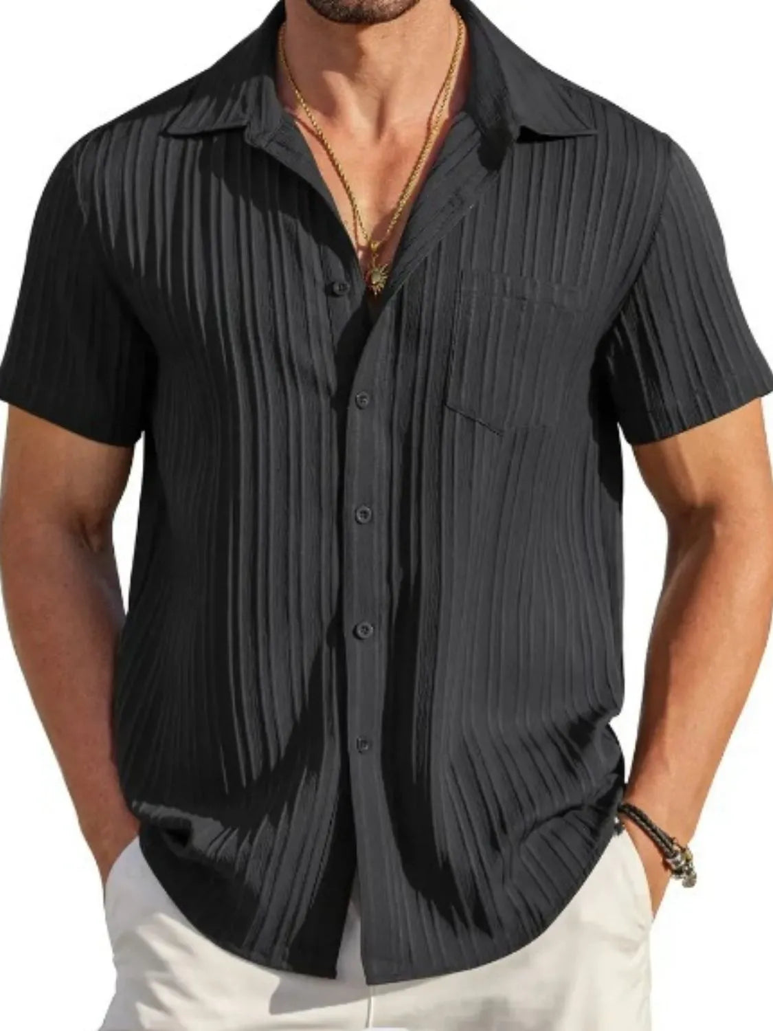 Man wearing a black textured short sleeve button-up shirt with white pants for a polished casual summer look.