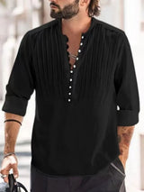 Man wearing a black button-detail long sleeve cotton polo with rolled sleeves and black pants.