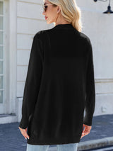 Woman wearing a black open front cardigan with blue jeans, layered over a white tank top for a casual everyday outfit.