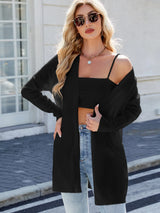 Woman wearing a black open front cardigan with blue jeans, layered over a white tank top for a casual everyday outfit.